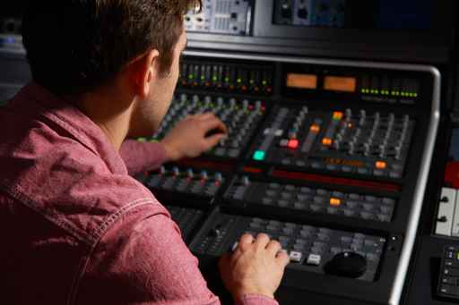 Engineer Working At Mixing Desk In Recording Studio